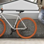 Homme tenant son téléphone à côté de son vélo personnalisé
