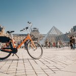 Vélo personnalisé orange devant le Louvre à Paris