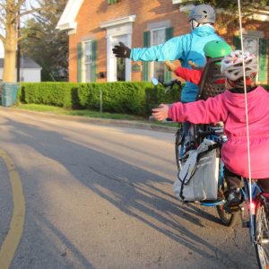 Famille à vélo signalant de la main qu'elle tourne gauche