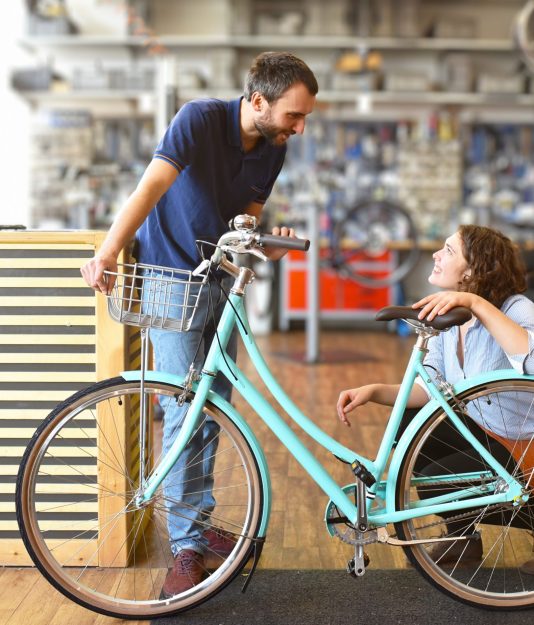 Vendeur et cliente avec son vélo en boutique